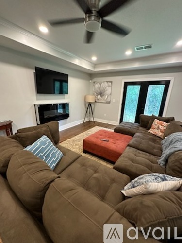 A living room with a brown couch and a ceiling fan.