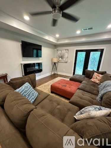 A living room with a brown couch and a ceiling fan.