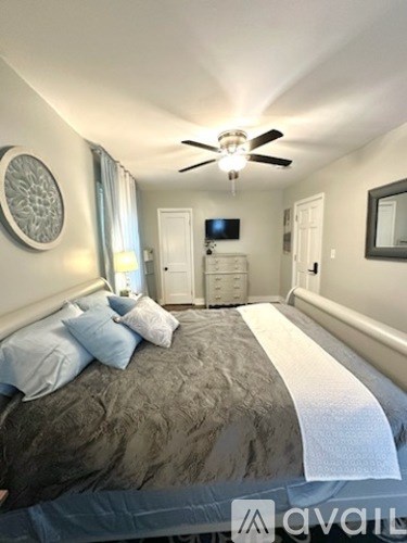 A bedroom with a large bed and a ceiling fan.