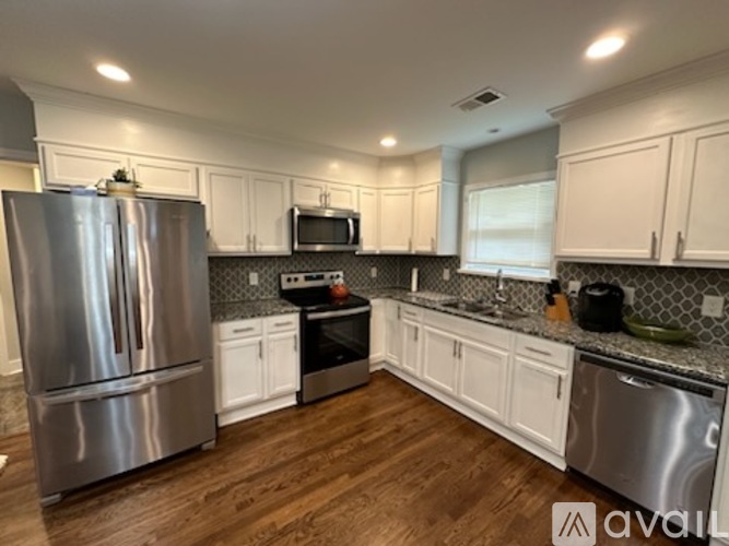 A kitchen with white cabinets and a stainless steel refrigerator.