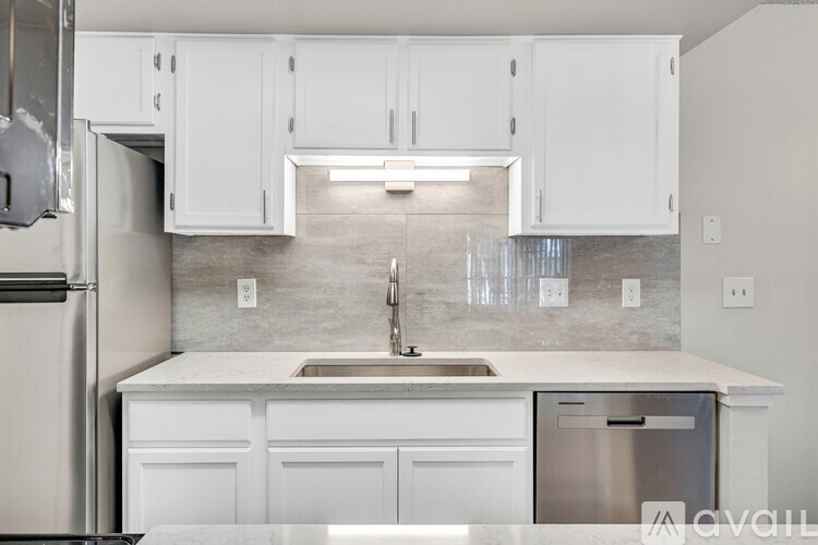 A kitchen with white cabinets and a marble countertop.