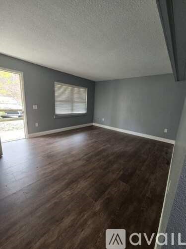 A room with wooden flooring and a window with blinds.