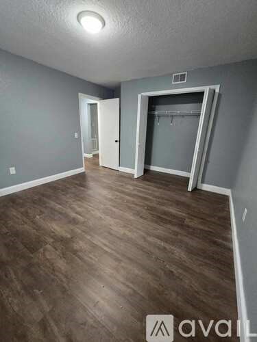 A room with wooden flooring and two doors, one of which is open.