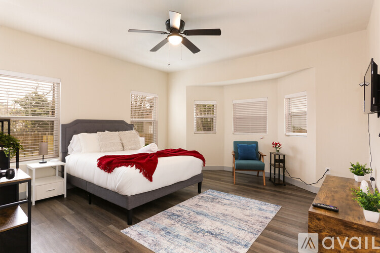 A bedroom with a bed, a chair, and a ceiling fan.