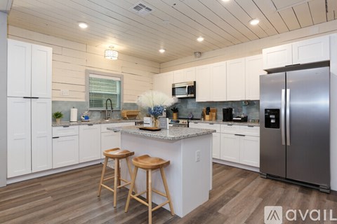 A kitchen with white cabinets and a wooden floor.