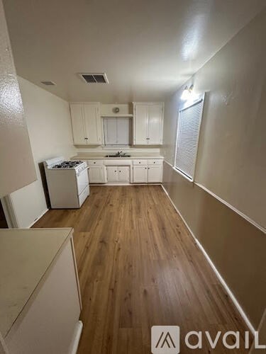 A kitchen with white cabinets and a wooden floor.