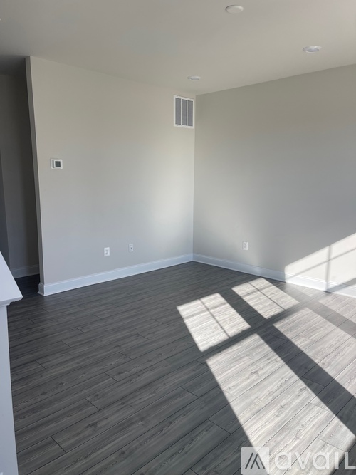 A room with a wooden floor and a window letting in sunlight.
