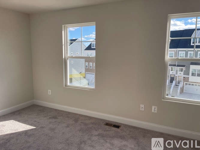 A room with two windows, one showing a view of a house and the other showing a building.