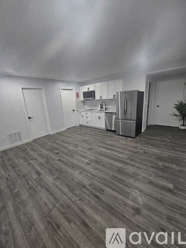 A kitchen area with wooden flooring and white walls.