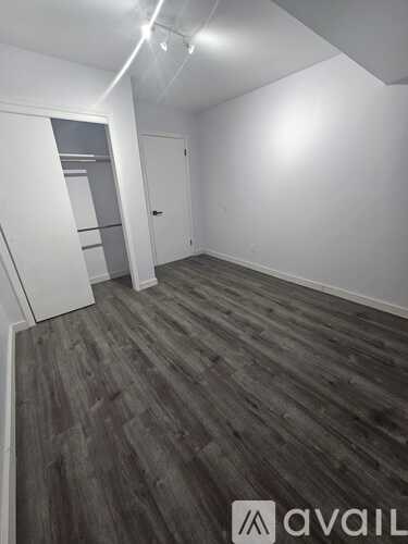 A room with wooden flooring and a white wall.