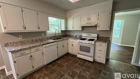 A kitchen with white cabinets and a granite countertop.