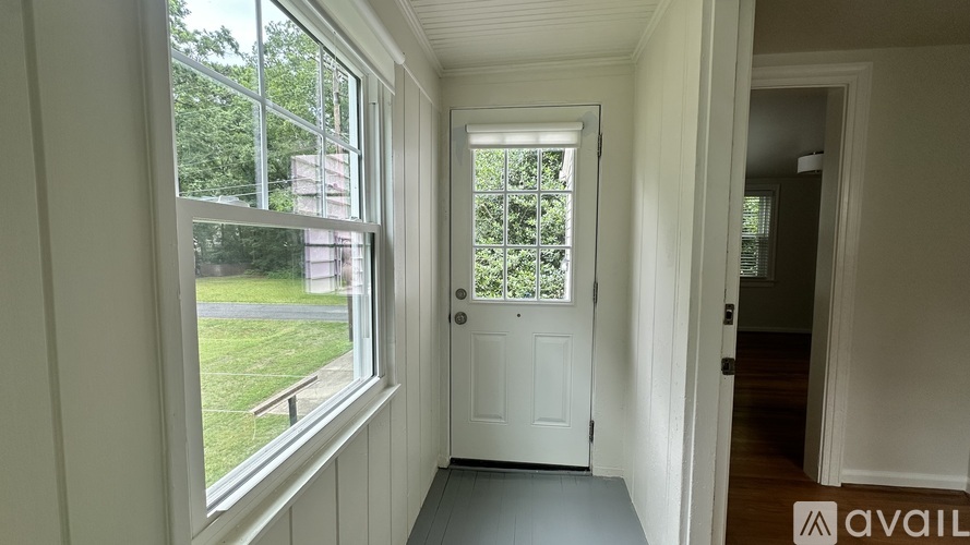 A room with a door and a window overlooking a green lawn.