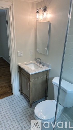 A bathroom with a toilet, sink, and mirror.