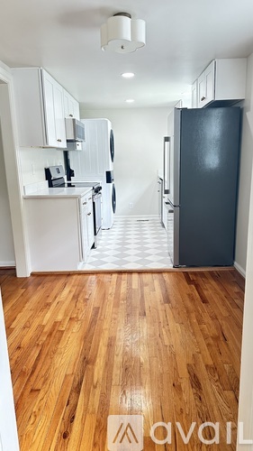 A kitchen with a black fridge and wooden floors.