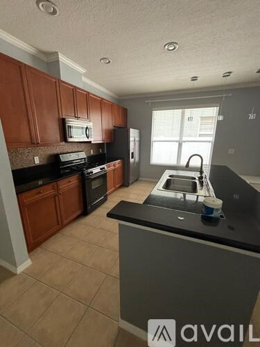A kitchen with brown cabinets and black countertops.