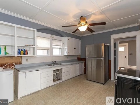 A kitchen with white cabinets and a stainless steel refrigerator.