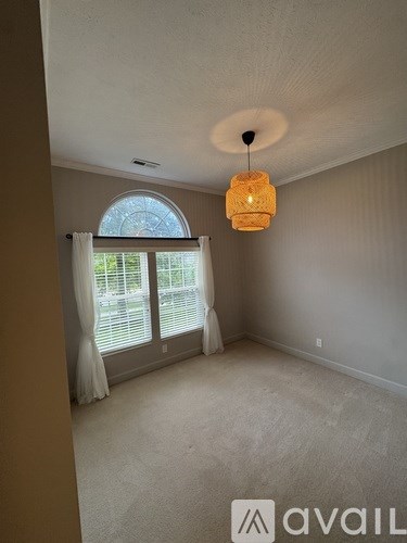 A room with a round window and a hanging light fixture.