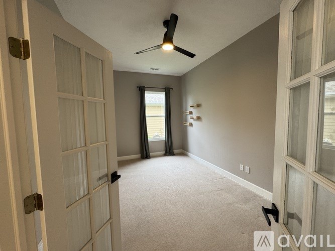 A room with a ceiling fan and a door leading to another room.