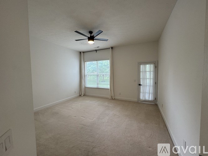 A room with a ceiling fan and carpeted floor.