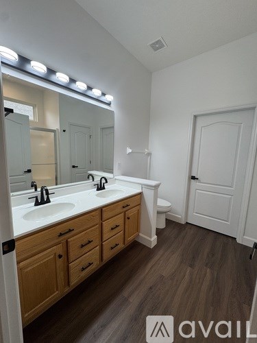 A bathroom with a vanity, mirror, and lights.