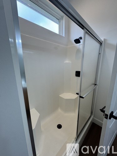 A white bathroom with a glass shower stall and a white door.