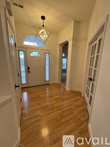A hallway with wooden floors and white walls leading to a door with a glass window.