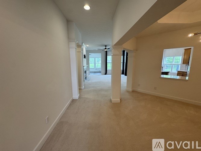 A spacious room with a carpeted floor and a window on the right side.