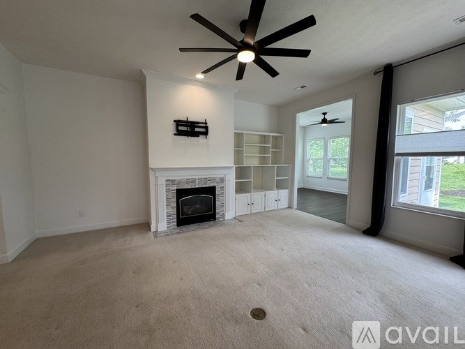 A living room with a fireplace and a ceiling fan.