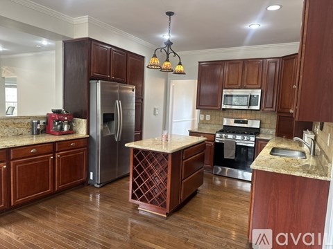 A kitchen with wooden cabinets and a marble island.