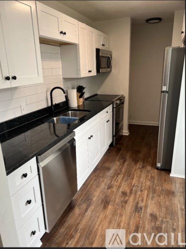 A kitchen with white cabinets and a black countertop.