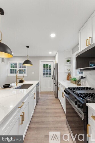 A modern kitchen with white cabinets and a black stove top.