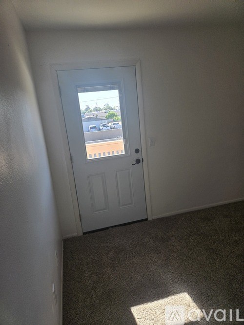 A white door with a window in the middle of a room.