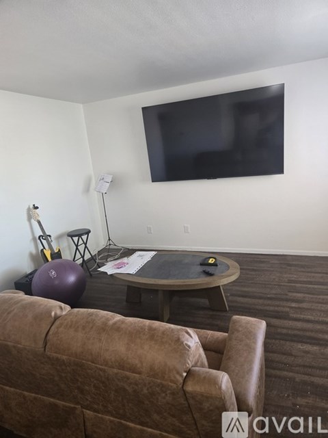 A living room with a brown couch and a flat screen TV mounted on the wall.