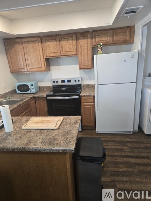A kitchen with a white refrigerator, wooden cabinets, and a granite countertop.