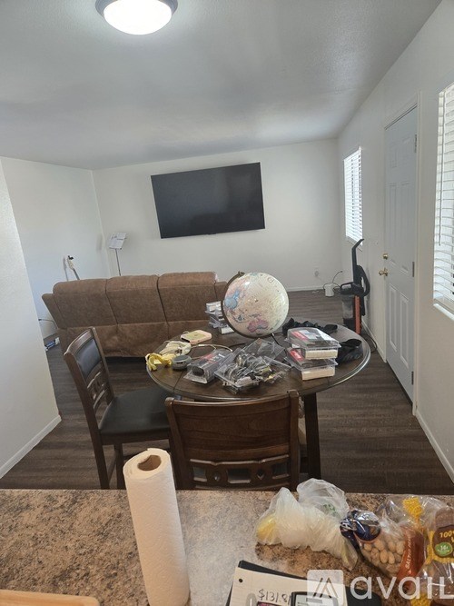 A living room with a couch, chairs, a table, and a television.