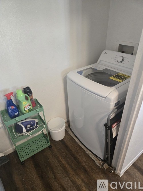 A white washing machine sits next to a green laundry basket.