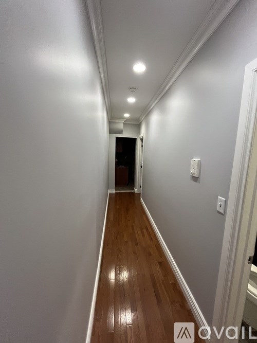 A long hallway with wood floors and white walls.