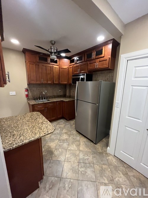 A kitchen with a granite counter top and a stainless steel refrigerator.