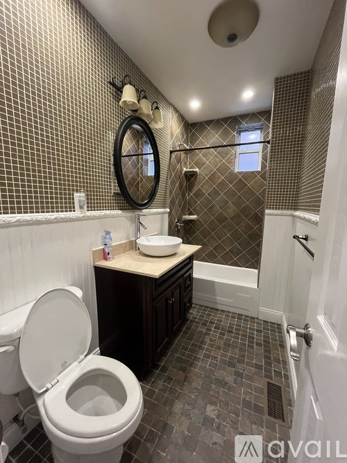 A bathroom with a toilet, sink, and tiled walls.