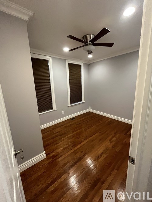 A room with a ceiling fan and wooden flooring.