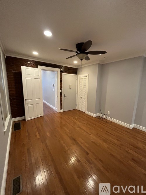 A room with a ceiling fan and wooden flooring.