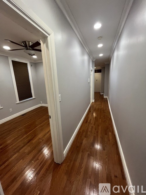 A long hallway with wood floors and a ceiling fan.