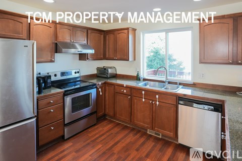 A kitchen with wooden cabinets and stainless steel appliances is for sale through TCM Property Management.