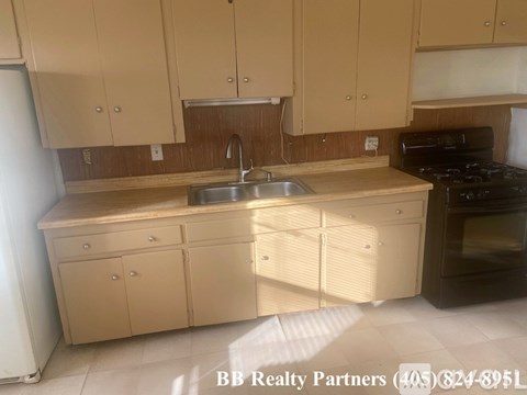 A kitchen with beige cabinets and a black stove top oven.