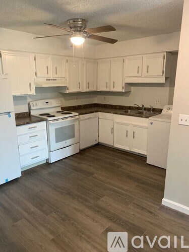 A kitchen with white cabinets and a wood floor.