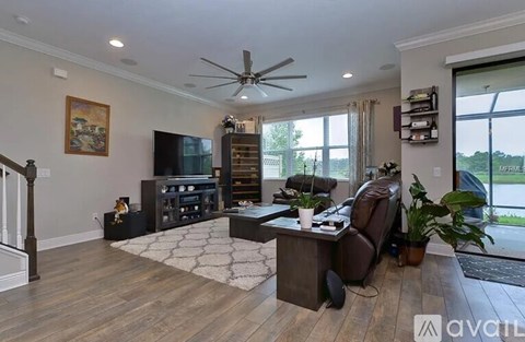 A living room with a brown leather couch and a wooden floor.