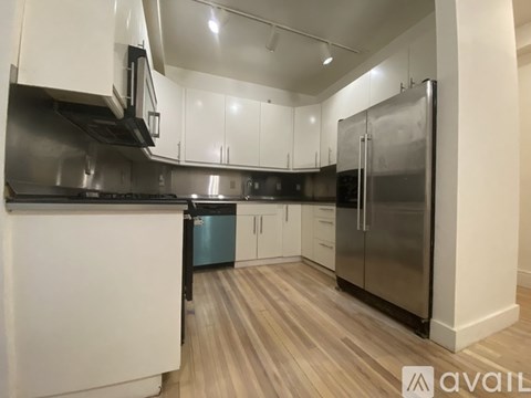A kitchen with white cabinets and a stainless steel refrigerator.