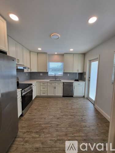 A kitchen with wooden floors and white cabinets is available for rent.