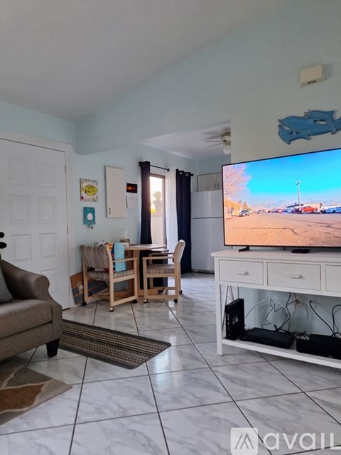A living room with a brown couch, a wooden chair, a white cabinet, and a television on a white stand.