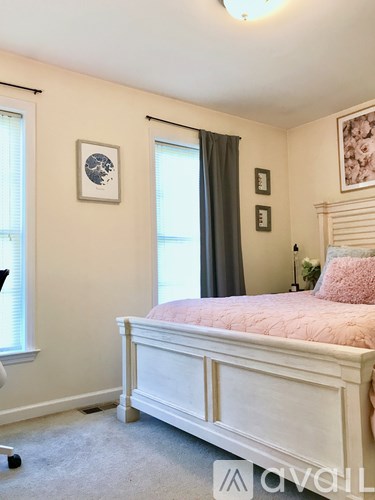A bedroom with a white bed and a pink pillow.